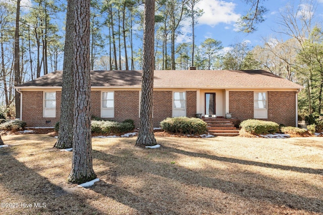 ranch-style home featuring brick siding, roof with shingles, and a front yard