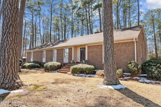 ranch-style house featuring a chimney and brick siding