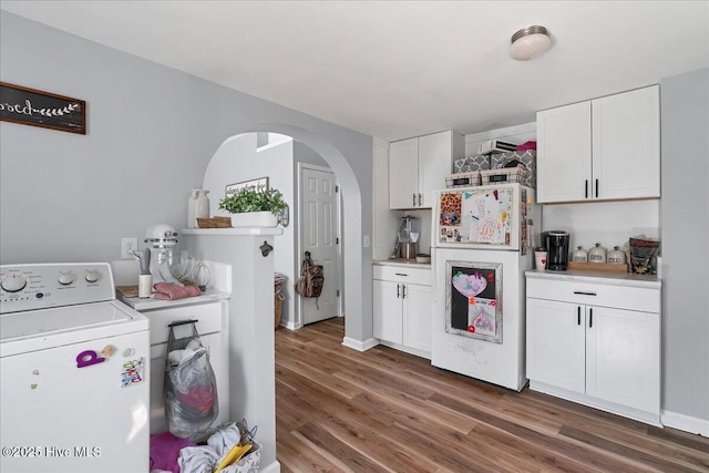 kitchen featuring washer / dryer, freestanding refrigerator, light countertops, and white cabinetry