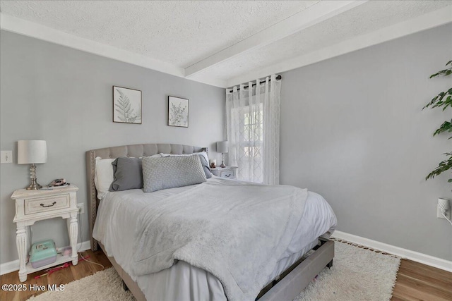 bedroom with a textured ceiling, baseboards, and wood finished floors