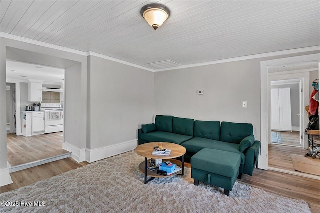 living room featuring baseboards, ornamental molding, and light wood-style floors