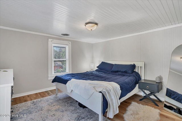 bedroom featuring baseboards, crown molding, and wood finished floors