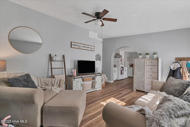 living room featuring ceiling fan, arched walkways, and wood finished floors