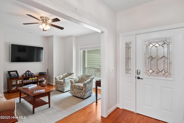 entryway featuring ceiling fan, baseboards, and light wood-style flooring