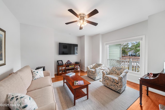 living room featuring baseboards, a ceiling fan, and wood finished floors