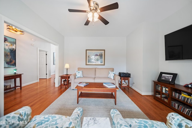 living area featuring a ceiling fan, wood finished floors, and baseboards