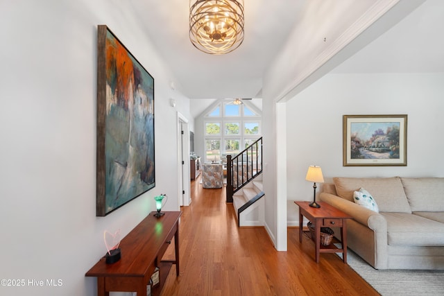 hall featuring baseboards, stairway, vaulted ceiling, wood finished floors, and a notable chandelier