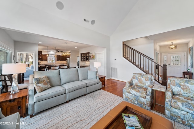 living area featuring stairway, wood finished floors, visible vents, and high vaulted ceiling