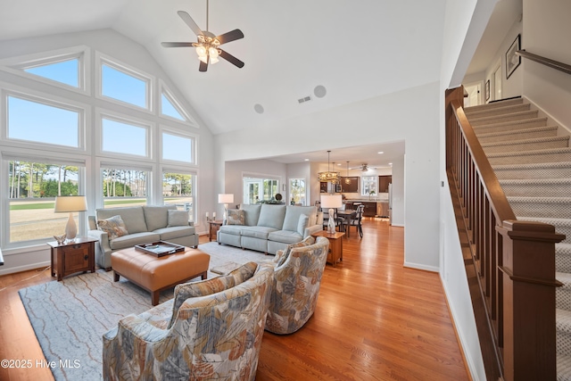 living room with stairway, plenty of natural light, light wood-style floors, and a ceiling fan