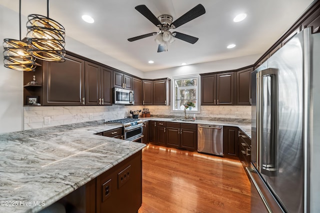 kitchen with high quality appliances, light wood-style flooring, a ceiling fan, a sink, and dark brown cabinetry