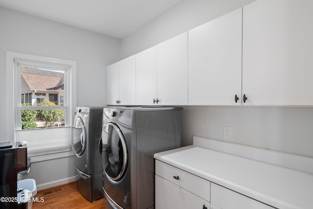 laundry area with visible vents, baseboards, light wood-type flooring, washer and dryer, and cabinet space