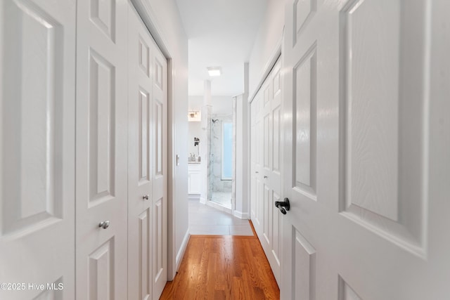 hallway featuring baseboards and light wood-style floors