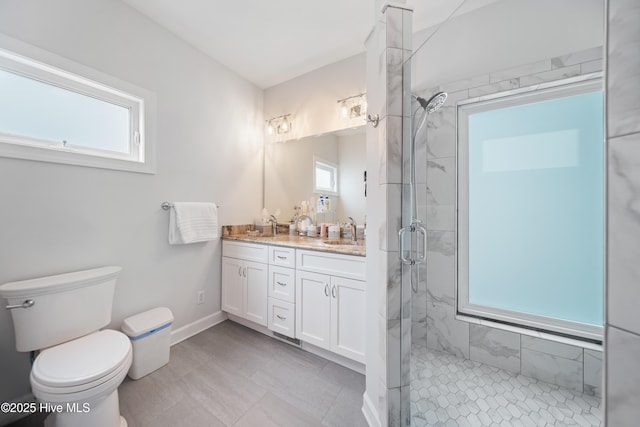 full bath with a sink, a marble finish shower, toilet, and a wealth of natural light