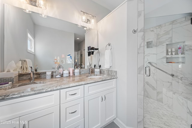 full bathroom with double vanity, a marble finish shower, and a sink