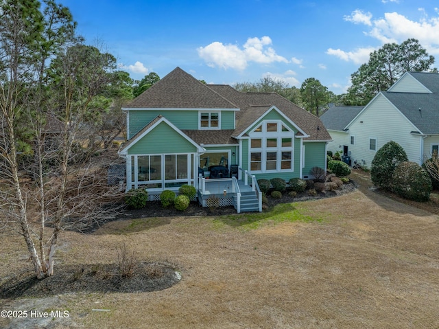 rear view of property featuring a wooden deck, a shingled roof, and a sunroom