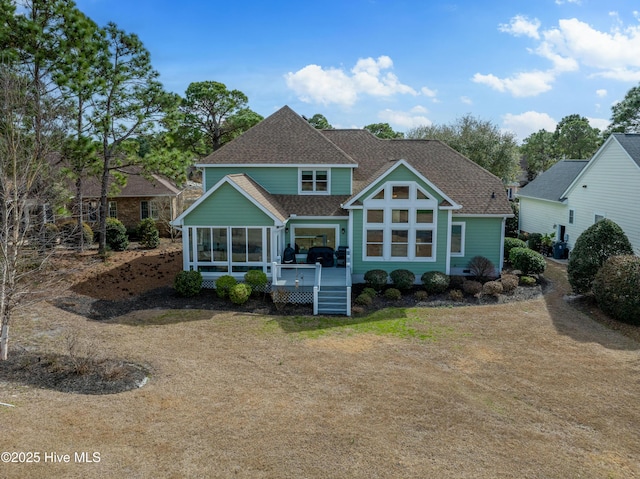 rear view of house featuring a deck, a sunroom, and roof with shingles