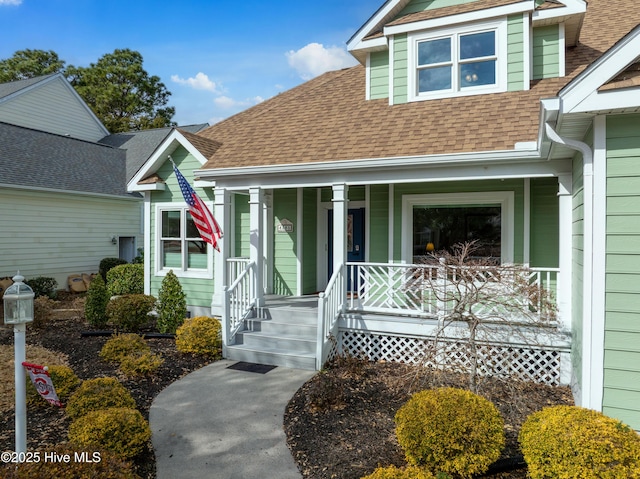 doorway to property featuring covered porch and roof with shingles