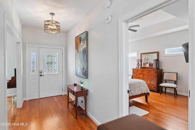 entryway with a notable chandelier, baseboards, and light wood-style floors