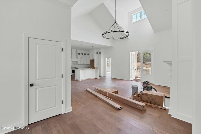 interior space with high vaulted ceiling, baseboards, a chandelier, and wood finished floors