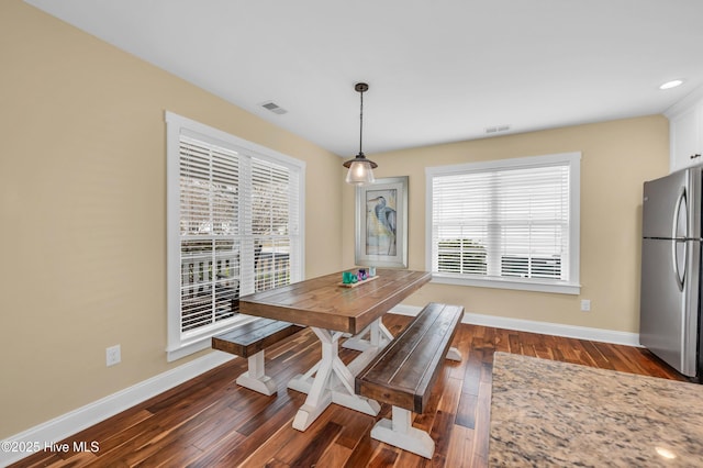 dining area with dark wood-type flooring, visible vents, and baseboards