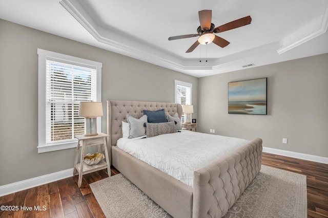 bedroom with wood finished floors, a raised ceiling, visible vents, and baseboards