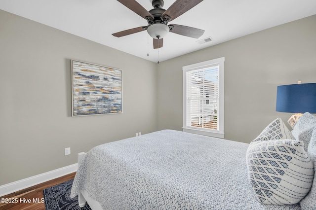 bedroom featuring ceiling fan, dark wood finished floors, visible vents, and baseboards