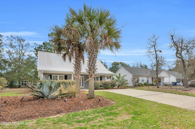 view of front of home with a front yard, concrete driveway, and metal roof