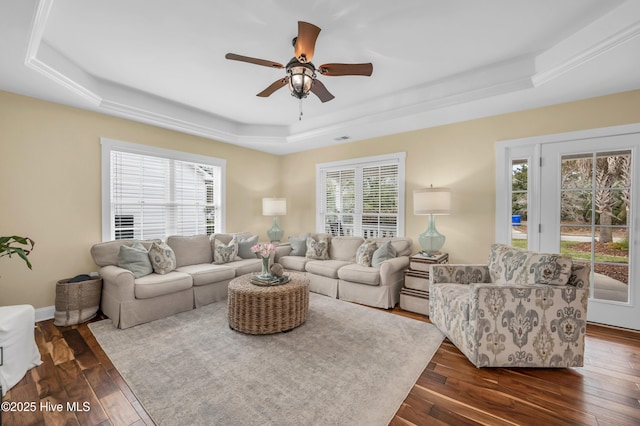 living room featuring dark wood-style floors, a tray ceiling, and a healthy amount of sunlight