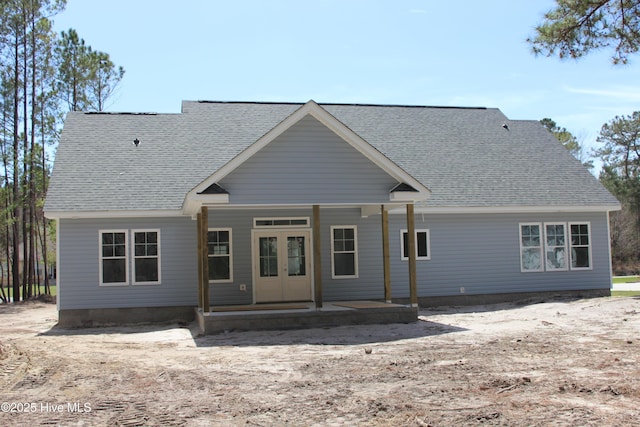 rear view of house featuring roof with shingles and a porch