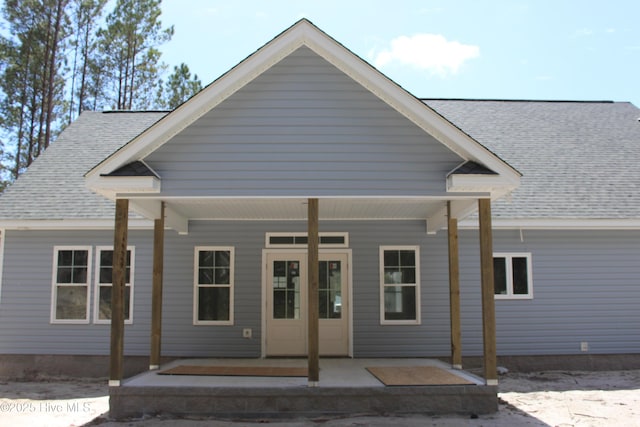 view of front facade with roof with shingles and a porch