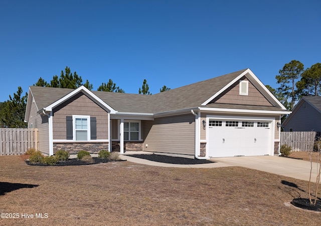 craftsman house featuring stone siding, an attached garage, fence, and driveway