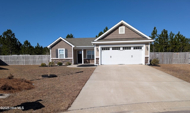 craftsman-style house with driveway, stone siding, an attached garage, and fence