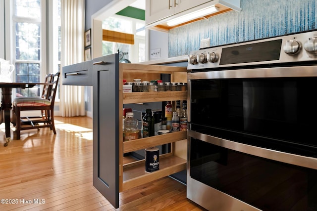 kitchen featuring light wood finished floors and multiple ovens