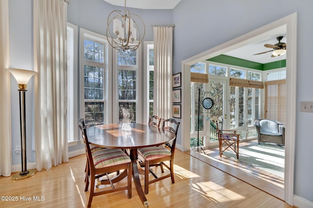 dining area featuring light wood-style floors, baseboards, and ceiling fan with notable chandelier