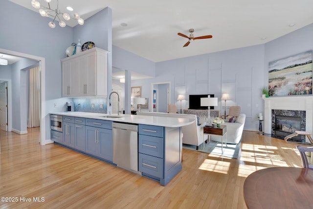 kitchen with stainless steel appliances, light countertops, open floor plan, white cabinetry, and a sink