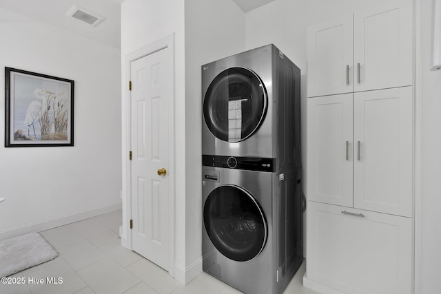 laundry room featuring baseboards, cabinet space, visible vents, and stacked washer / drying machine