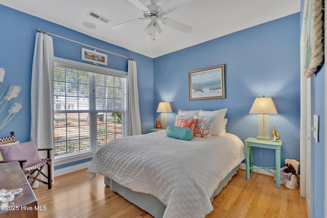 bedroom featuring ceiling fan, light wood-type flooring, visible vents, and baseboards