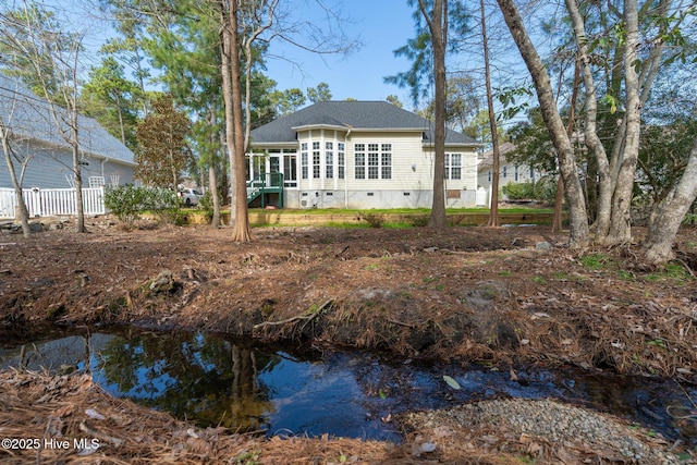 rear view of house featuring a sunroom, crawl space, and fence