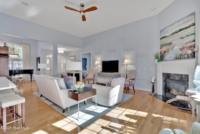 living room featuring a ceiling fan, light wood finished floors, and a premium fireplace