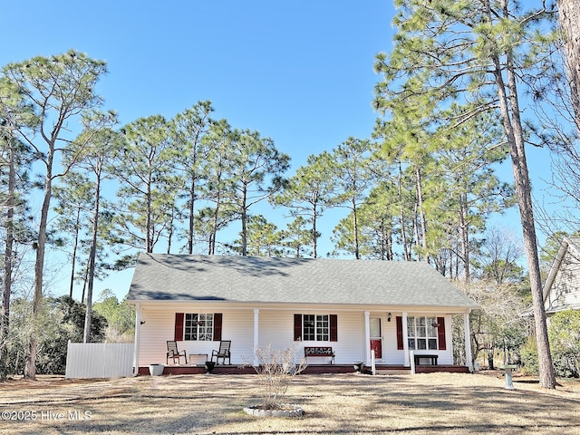 ranch-style home with a shingled roof, fence, a porch, and a front yard