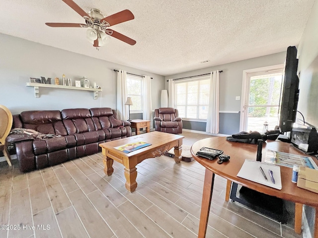 living room with a ceiling fan, a textured ceiling, and wood finished floors