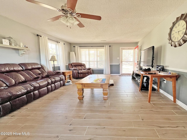 living area with ceiling fan, a textured ceiling, and light wood-type flooring