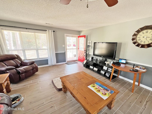 living area with ceiling fan, wood finish floors, a textured ceiling, and baseboards