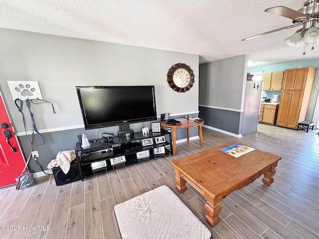 living area with a ceiling fan, light wood-type flooring, a textured ceiling, and baseboards