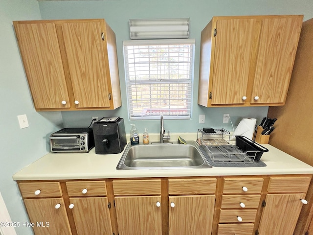 kitchen featuring a toaster, light countertops, and a sink