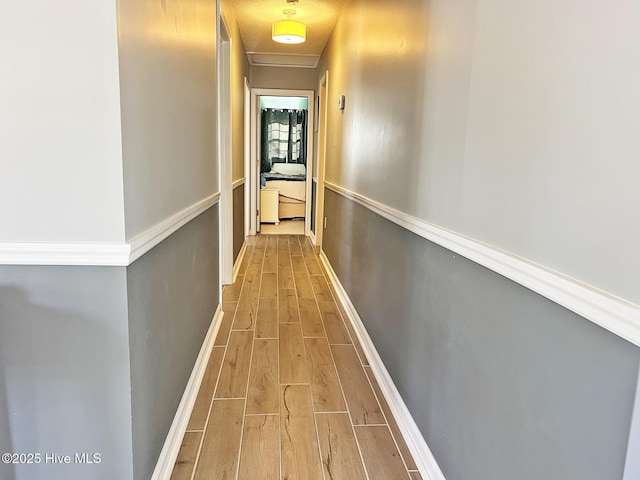 hallway featuring wood finish floors and baseboards