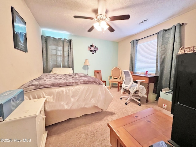 bedroom featuring a textured ceiling, ceiling fan, visible vents, and light colored carpet