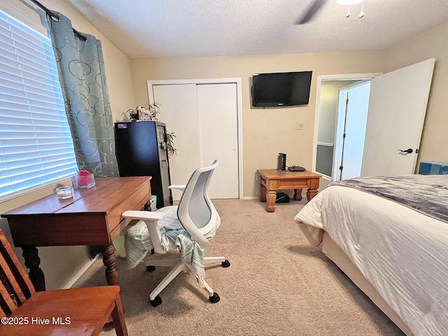 bedroom with a ceiling fan, a closet, light carpet, and a textured ceiling