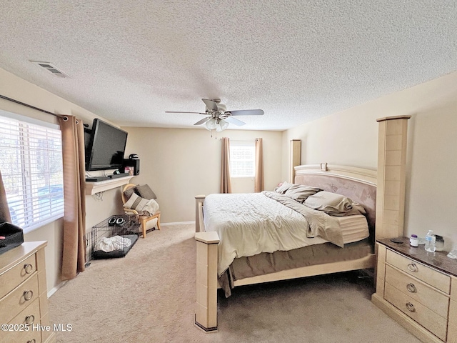 bedroom with light carpet, ceiling fan, a textured ceiling, and visible vents