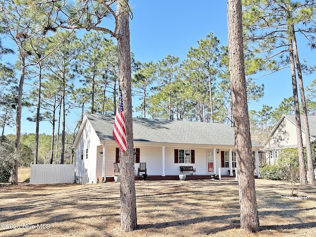 view of front of property featuring covered porch, fence, and roof with shingles